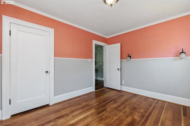1902 N Terry St, Portland, OR 97217 - empty room with wood-type flooring, a wainscoted wall, crown molding, baseboards, and a textured ceiling