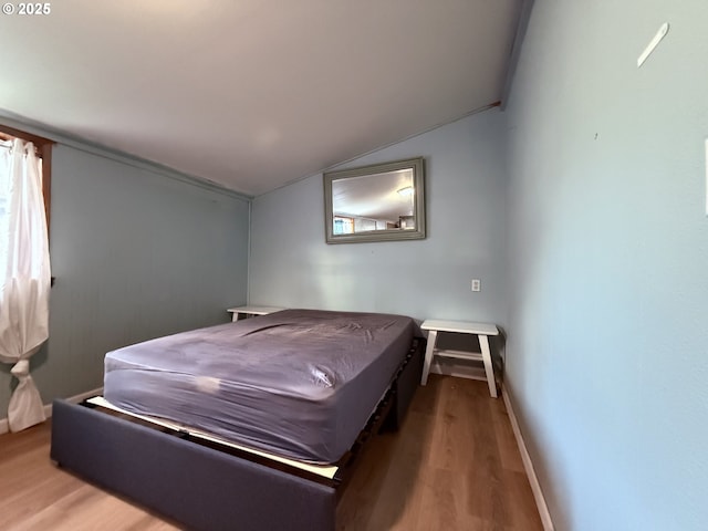 bedroom with lofted ceiling, baseboards, and wood finished floors