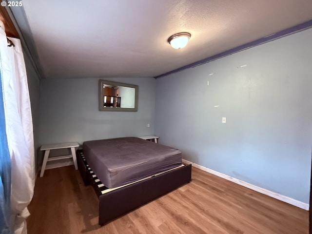 bedroom featuring wood finished floors and baseboards