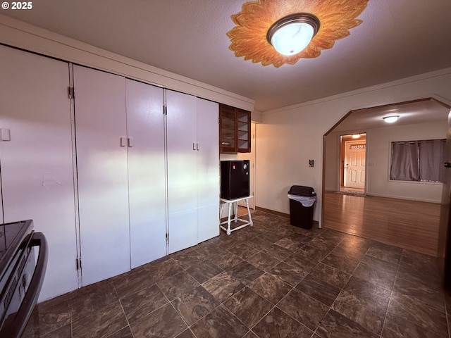 interior space with glass insert cabinets, baseboards, and arched walkways