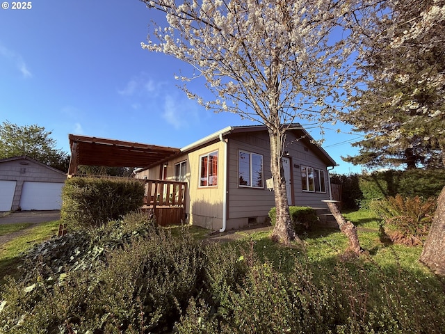 view of home's exterior with an outbuilding, a wooden deck, and a detached garage
