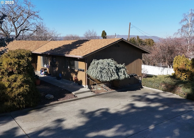 view of side of property with roof with shingles and fence