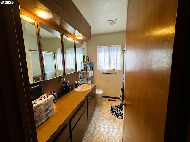 bathroom with toilet, tile patterned flooring, visible vents, and a sink