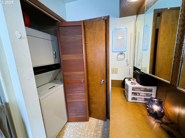 clothes washing area featuring stacked washer and dryer and laundry area