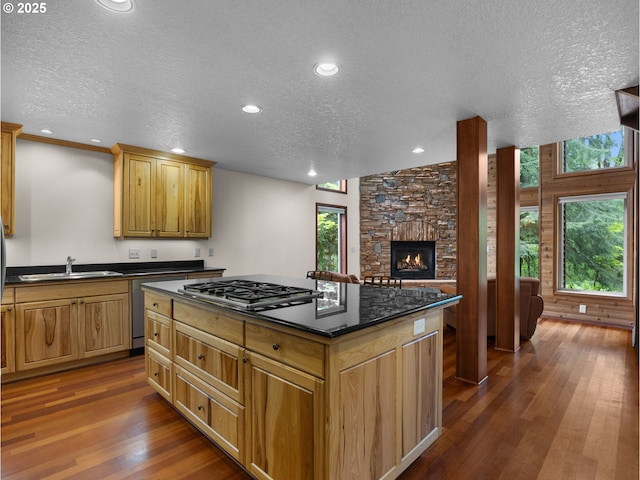 24982 E Tillicum St, Welches, OR 97067 - kitchen with stainless steel gas stovetop, a sink, dark wood-style flooring, a textured ceiling, and a stone fireplace