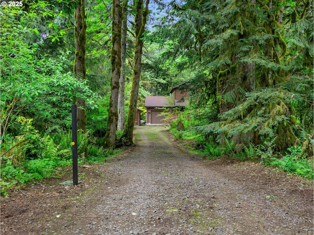 24982 E Tillicum St, Welches, OR 97067 - view of front facade with dirt driveway, a view of trees, and a garage