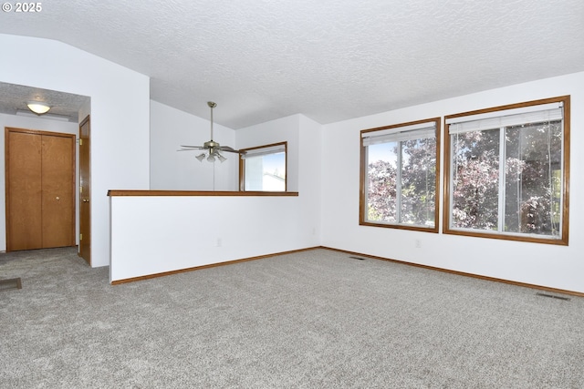 empty room with lofted ceiling, carpet floors, a textured ceiling, ceiling fan, and baseboards