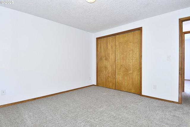 unfurnished bedroom featuring carpet floors, a closet, baseboards, and a textured ceiling