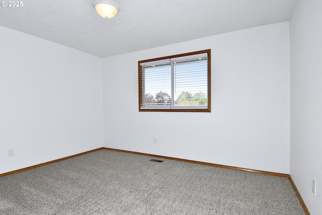 carpeted empty room featuring baseboards and a textured ceiling