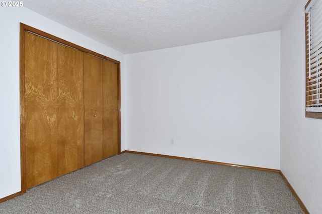 unfurnished bedroom with carpet floors, a closet, baseboards, and a textured ceiling