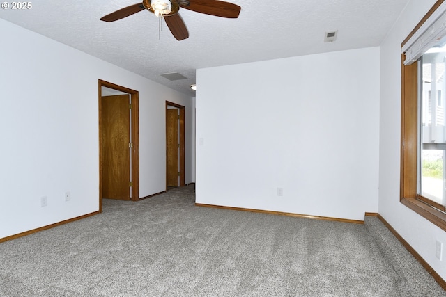 carpeted empty room featuring ceiling fan, a textured ceiling, and baseboards