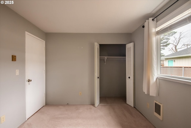 unfurnished bedroom featuring a closet, light carpet, and visible vents