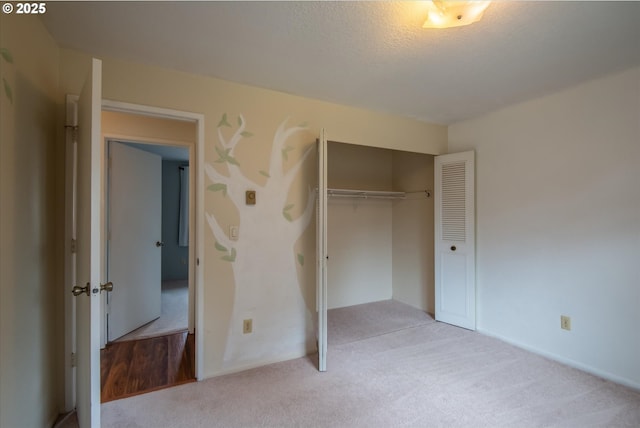 unfurnished bedroom with a textured ceiling, a closet, and light colored carpet