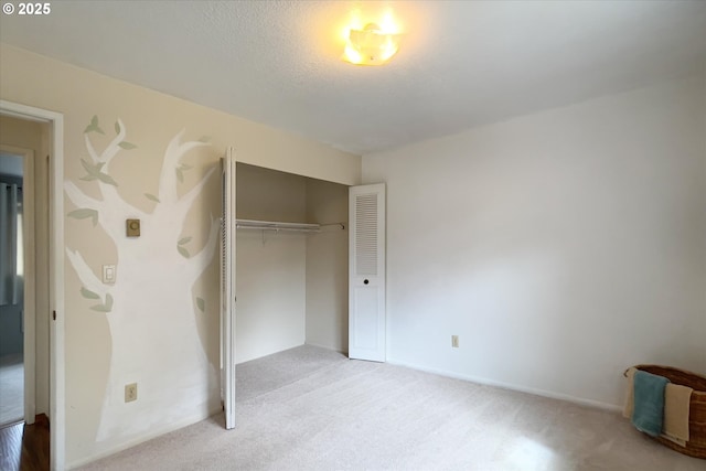 unfurnished bedroom featuring a textured ceiling, a closet, and light colored carpet