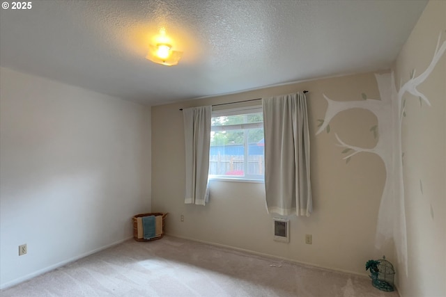 spare room featuring carpet, visible vents, and a textured ceiling