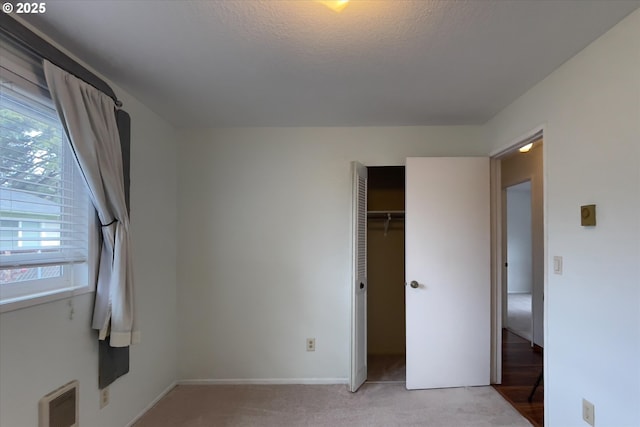 unfurnished bedroom featuring light carpet, a textured ceiling, and baseboards