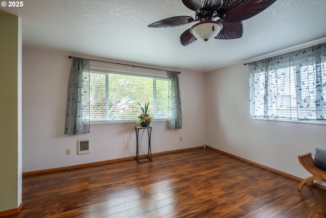 spare room featuring a textured ceiling, dark wood finished floors, a ceiling fan, and baseboards