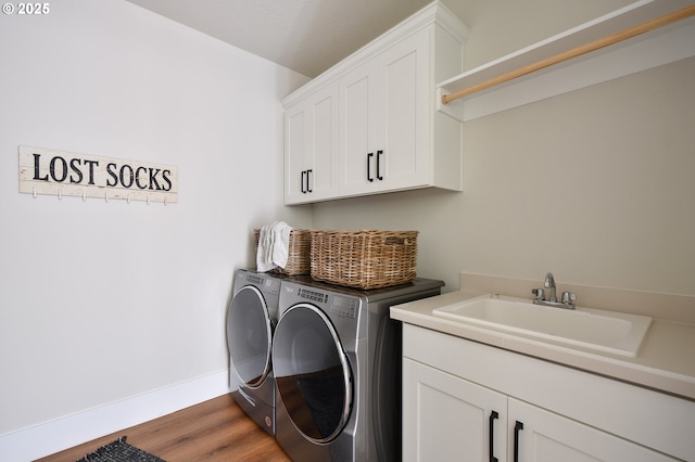 laundry room with washing machine and dryer, wood-type flooring, cabinets, and sink