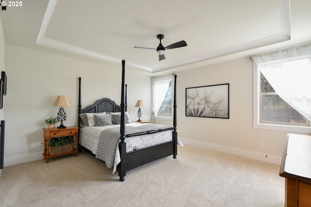 bedroom featuring ceiling fan, light colored carpet, and a tray ceiling