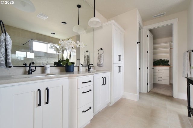 bathroom with tile patterned floors, walk in shower, tasteful backsplash, and vanity