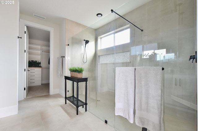 bathroom with visible vents, baseboards, tile patterned floors, a stall shower, and a walk in closet