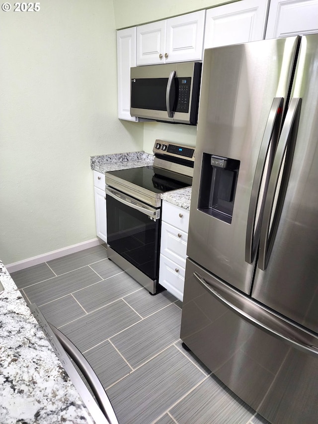 kitchen featuring light stone countertops, stainless steel appliances, and white cabinetry