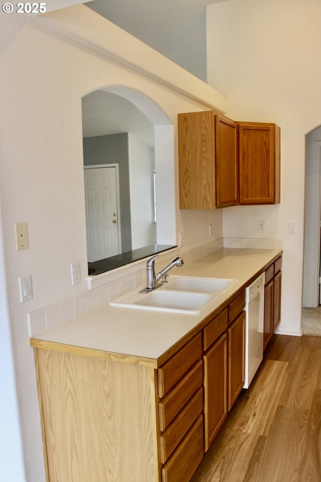 203 Robin Ct, Creswell, OR 97426 - kitchen featuring a sink, dishwasher, arched walkways, light wood finished floors, and brown cabinetry