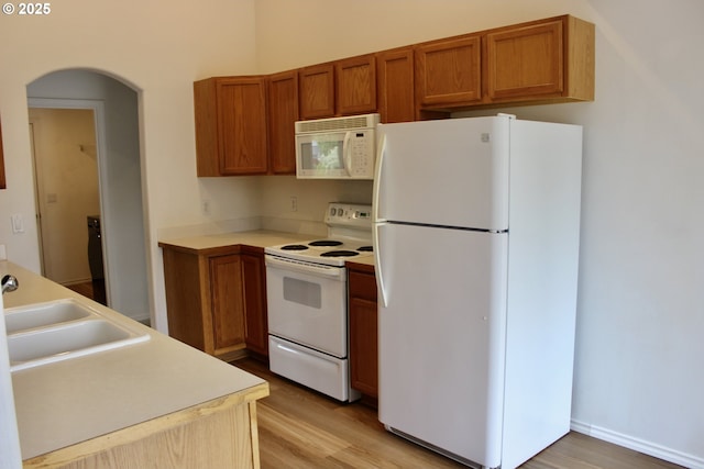 203 Robin Ct, Creswell, OR 97426 - kitchen featuring white appliances, light wood-style flooring, brown cabinetry, and arched walkways