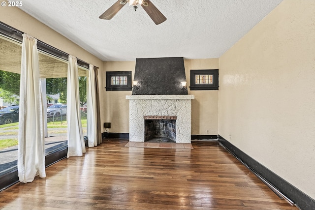 530 21st Ave, Longview, WA 98632 - unfurnished living room featuring a stone fireplace, hardwood / wood-style floors, a ceiling fan, a textured ceiling, and a textured wall