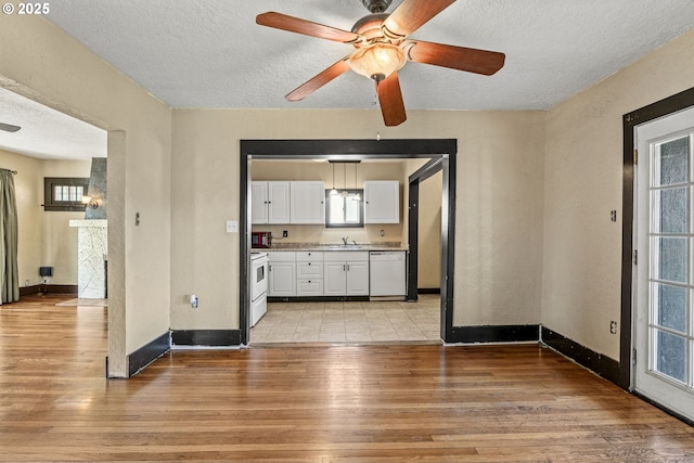530 21st Ave, Longview, WA 98632 - unfurnished living room with a textured ceiling, light wood-style flooring, baseboards, a ceiling fan, and a sink