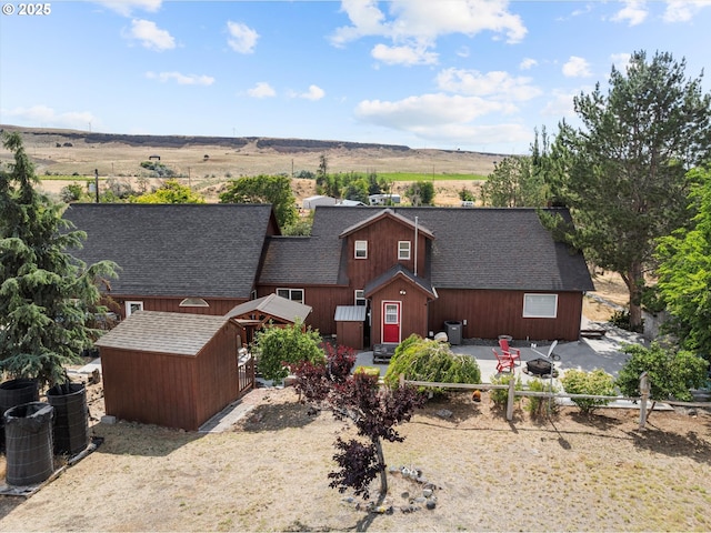 18122 Hulden Ln, Arlington, OR 97812 - view of front of house with a fire pit, roof with shingles, a storage unit, and a patio