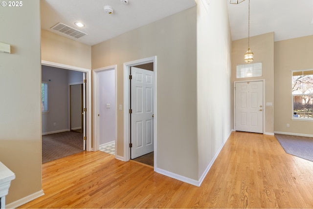 entryway featuring light wood-style floors, a high ceiling, visible vents, and baseboards