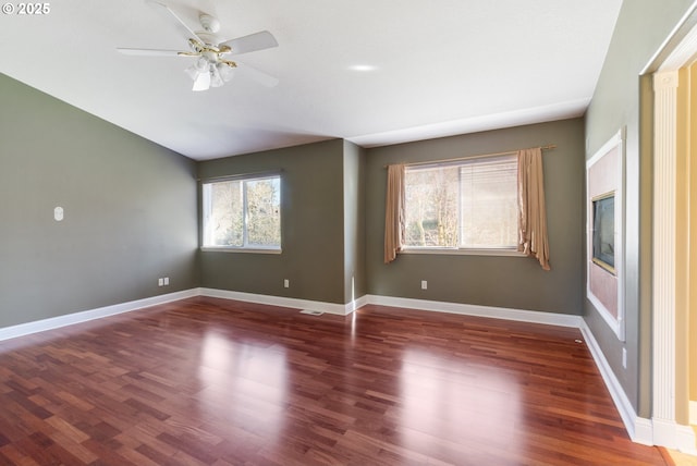 empty room with ceiling fan, baseboards, and wood finished floors