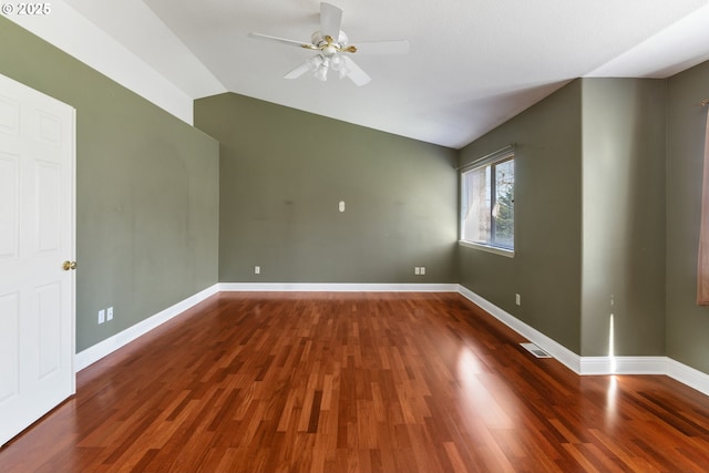 empty room featuring vaulted ceiling, wood finished floors, and baseboards