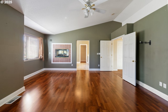 interior space featuring baseboards, visible vents, vaulted ceiling, and wood finished floors