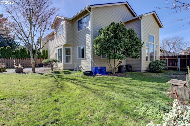 rear view of property with a lawn and fence