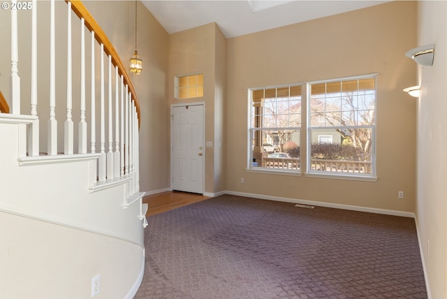 foyer entrance featuring carpet flooring, baseboards, and stairs