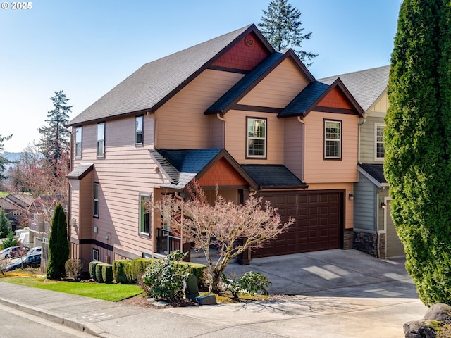 craftsman-style house featuring a shingled roof, concrete driveway, an attached garage, and stone siding