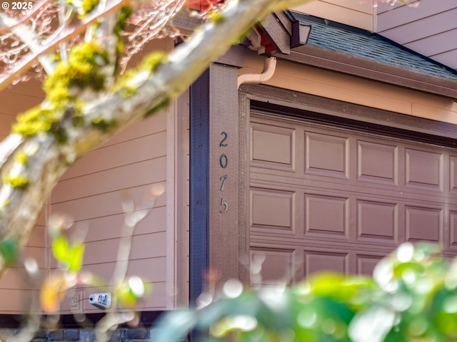 exterior details featuring gutters, roof with shingles, and a downspout