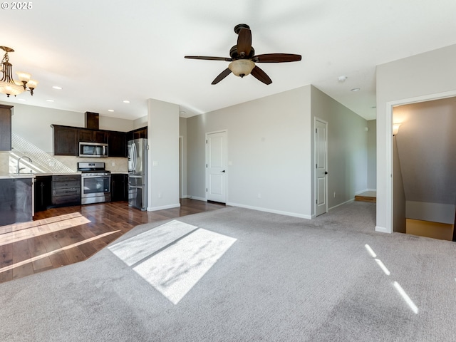 unfurnished living room featuring carpet, a sink, and baseboards