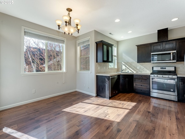 kitchen featuring stainless steel appliances, a sink, light countertops, decorative backsplash, and wood-type flooring