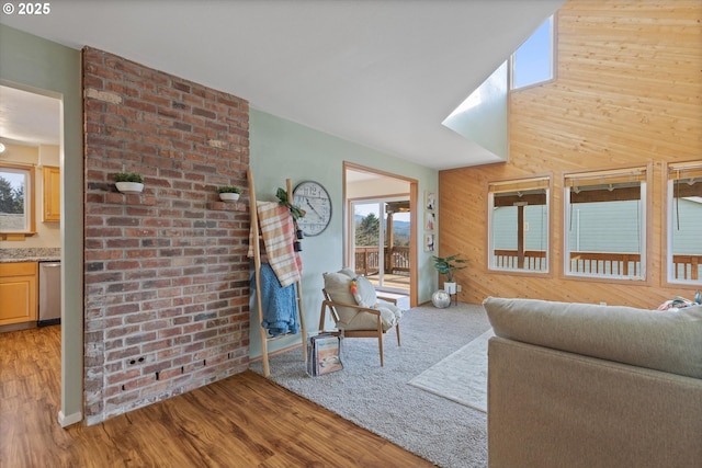 living room featuring a brick fireplace, wooden walls, hardwood / wood-style floors, and a high ceiling