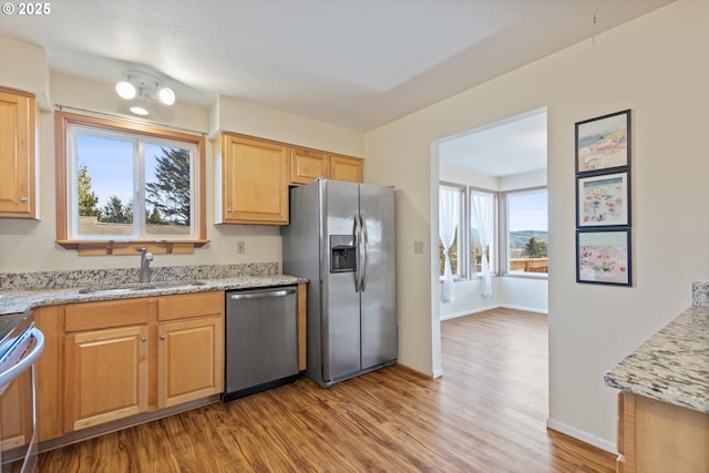 kitchen featuring light stone counters, sink, stainless steel appliances, and light wood-type flooring