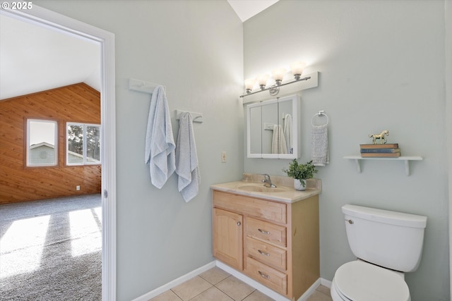 bathroom with tile patterned floors, toilet, lofted ceiling, vanity, and wooden walls