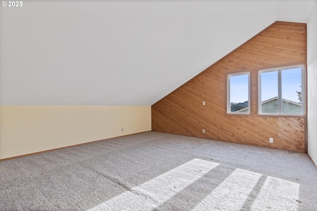 additional living space with carpet floors, wooden walls, and vaulted ceiling