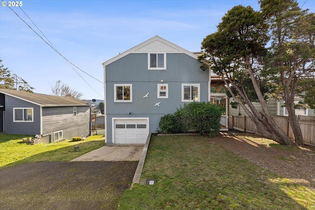 rear view of property featuring a garage and a yard