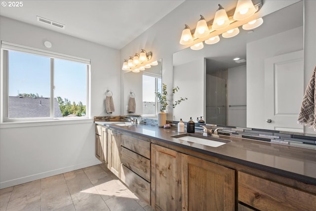 bathroom with tile patterned flooring, vanity, a wealth of natural light, and a shower with shower door