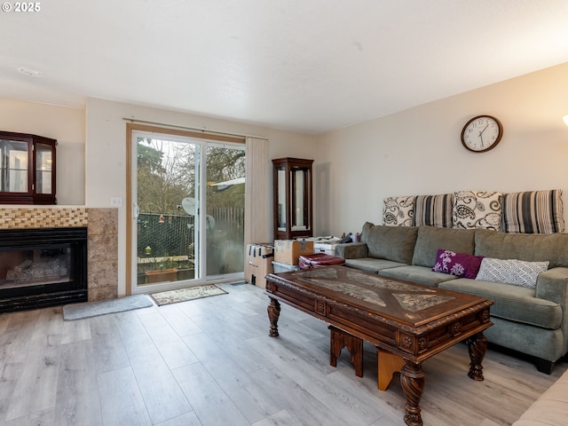 living room with a tile fireplace and light hardwood / wood-style floors