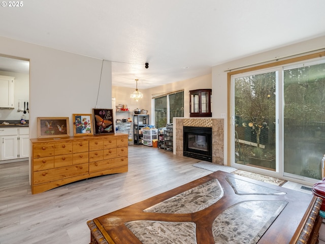 living room with a tile fireplace, a chandelier, and light wood-type flooring