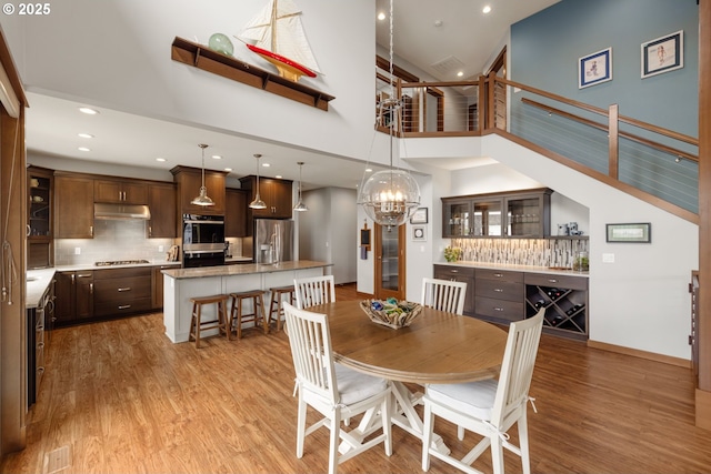 8866 Ocean Crest Ln, Manzanita, OR 97130 - dining space with light wood finished floors, a chandelier, recessed lighting, and a towering ceiling